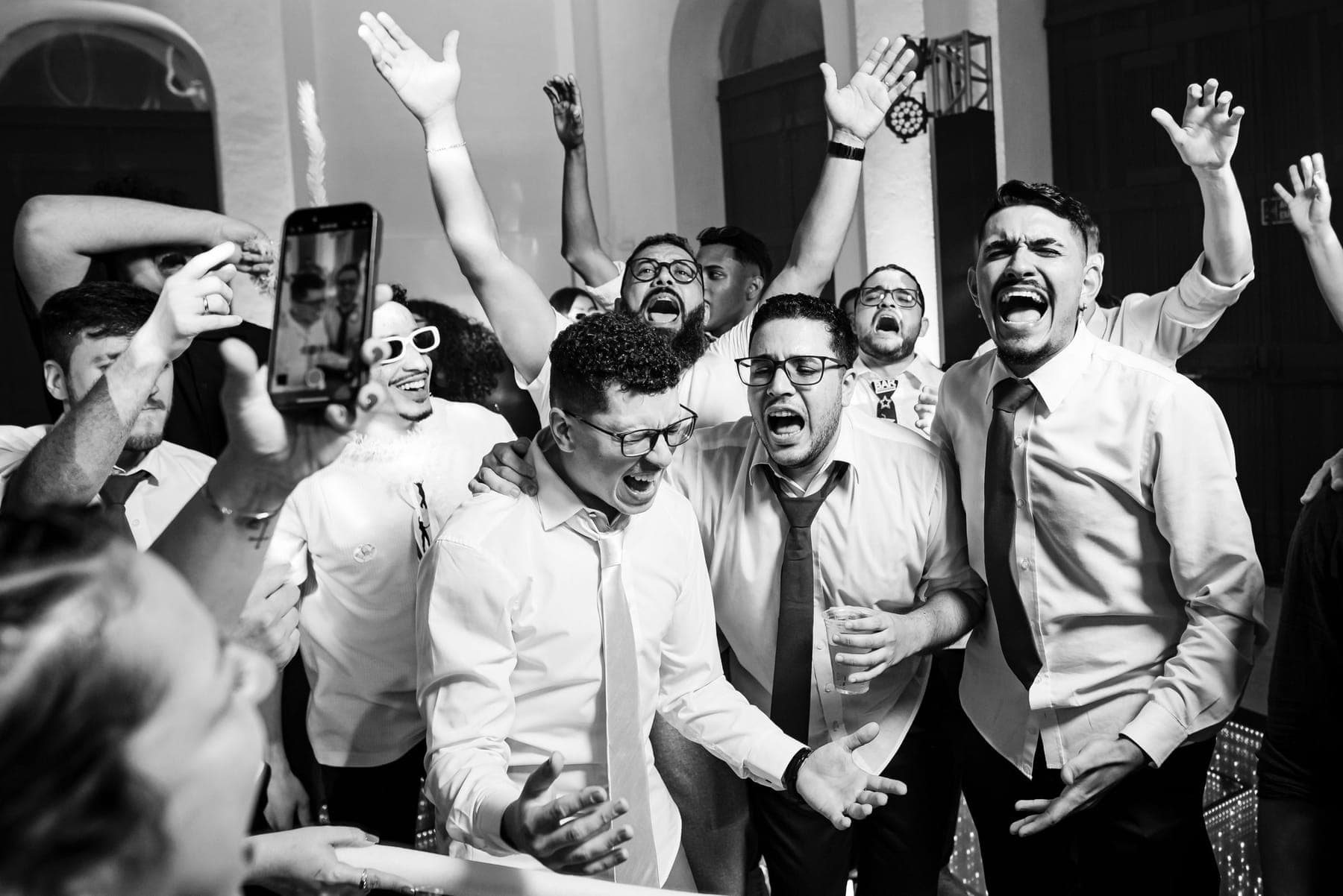 Men in shirtsleeves cheering at a party, in black and white