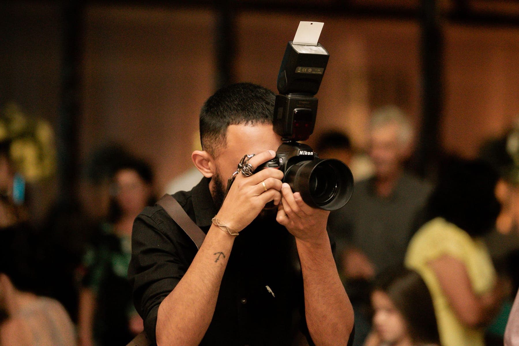 A photographer at an indoor event, camera raised, flash on