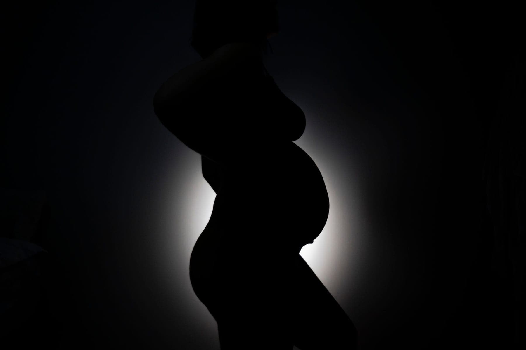 A maternity silhouette against a dark ground