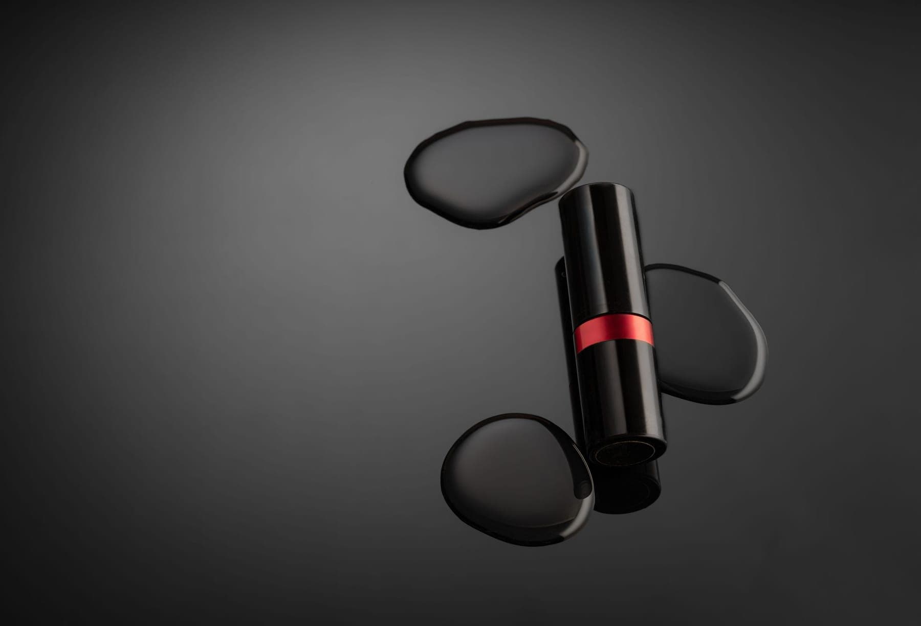A lipstick resting on dark stones