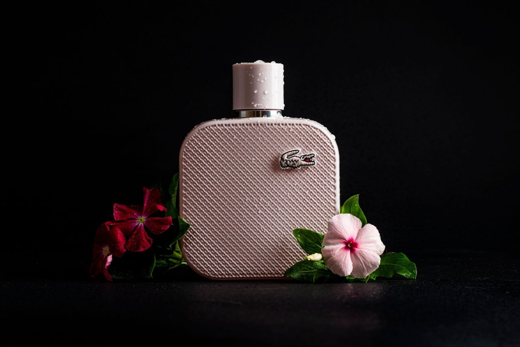A perfume bottle with flowers on dark ground