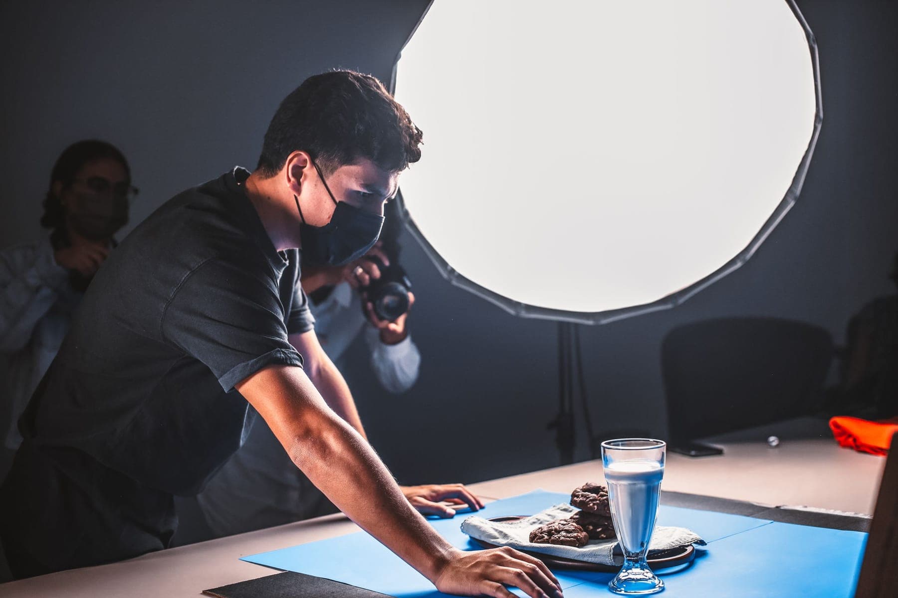 A photographer arranging a tabletop set under a softbox