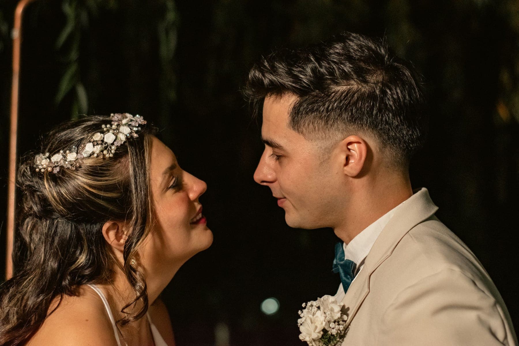 A bride and groom close together, eyes on each other, in low warm light