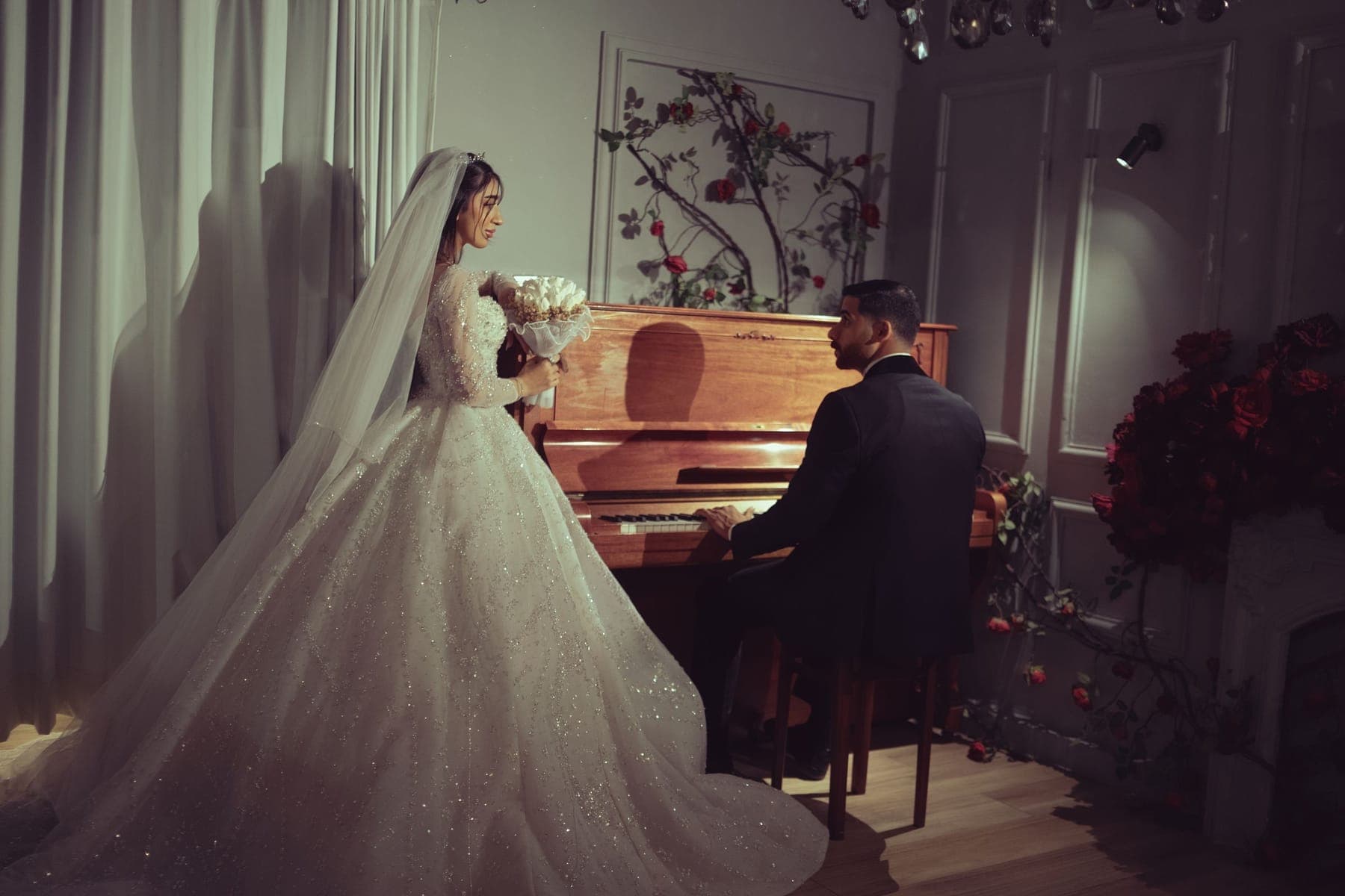 A bride with her bouquet and the groom at a piano, in Baghdad